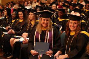 Undergraduate students sitting holding diplomas
