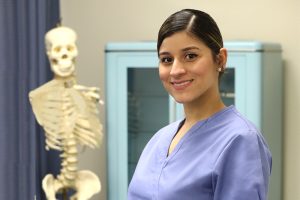 Nursing student standing in front of a skeleton