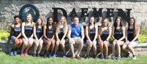 Women's cross country team sitting in front of Daemen College stone sign at the front of campus.