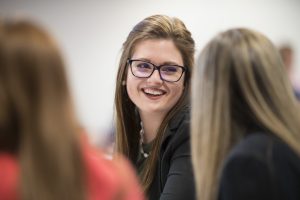 Female graduate student talking to others and smiling