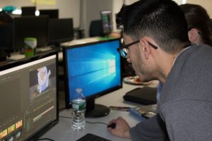 Daemen Animation student Lucas Santos leaning over working at a computer