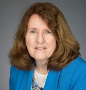 Patricia Johnson sitting for headshot in front of grey background