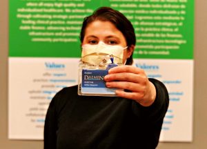 Ashley Giaquinto wearing a face mask holding her Daemen ID out in front of her