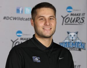 Ryan Grandits in a Daemen College polo standing infront of an athletics backdrop