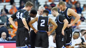 Men's basketball team in a time out huddle with Coach McDonald