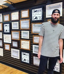 Dan Erickson standing in front of his artwork hung on a wall