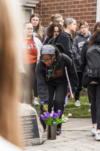 Students place purple flowers in front of a memorial for Jennifer "Jenny"McAlmont