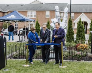 President Gary Olson, Paula Savage, and Chairman John Yurtchuk cut the ribbon in front of the new peace garden and statue at Daemen University.