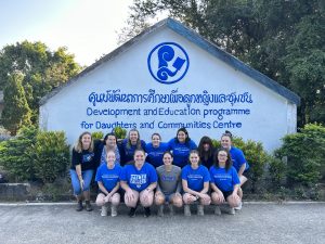 Students pose in front of a sign at the DEPDC in Thailand