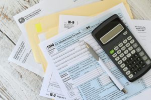 Generic picture of tax prep materials including tax forms and a calculator.
