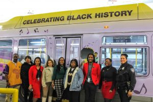 Amani Fanning and others in front of a bus with her winning artwork.