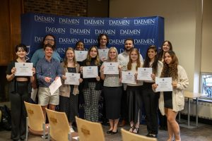 Group of students holding certificates in front of a Daemen step-and-repeat background.