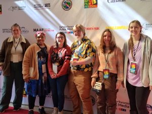 Six students dressed in colorful clothing standing in front of a step and repeat during the Buffalo International Film Festival. 