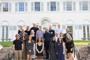 Group of 19 college students and faculty in front of white house on college campus