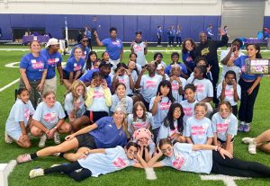 Group of over 25 female flag football players posing for photo on indoor astroturf