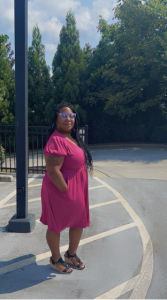 African American woman with long hair in fuchsia dress standing in a parking lot