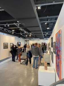 Group of people in an art gallery looking at artwork hanging on white walls