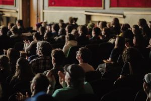 Theater crowd seated looking at the movie screen