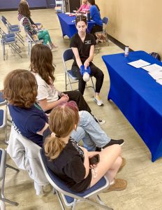Woman sitting down demonstrating CPR to three other women who are also sitting