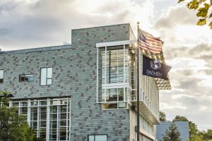 Brick building with windows and the U.S. flag and Daemen University flag flying on a flag pole