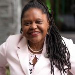 African American woman with long dark hair wearing a light pink blouse and blazer.