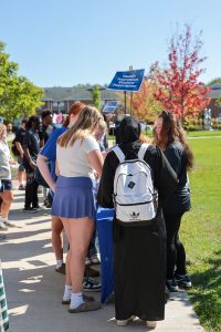Group of students outside standing around a table on college campus