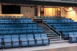 Auditorium with several rows of blue seats and a film room behind them