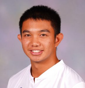 Young Asian male with dark hair wearing a white t-shirt in front of a gray background