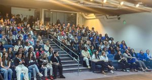 Small auditorium with several rows of seats filled with college students.