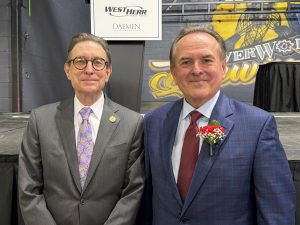 Two men wearing a gay suit and blue suit with white shirts and ties standing together