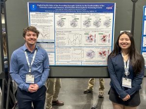 Two college students standing in front of a scientific poster with images and text on it