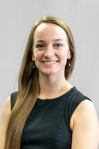 Female with long, light brown hair over her right shoulder, wearing a sleeveless dress