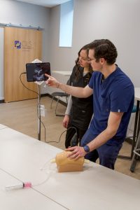 Professor and student looking at an ipad that is simulating an ultrasound on a knee joint.