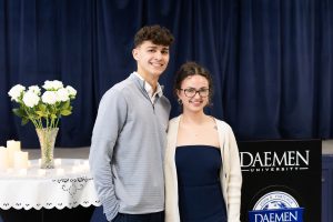A male and female college student standing together in the front of a room
