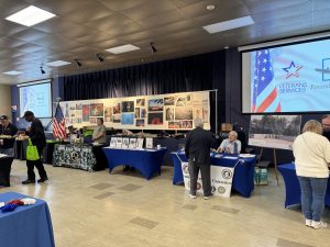 Room with photos on display, tables set up and large screens with a slide presentation