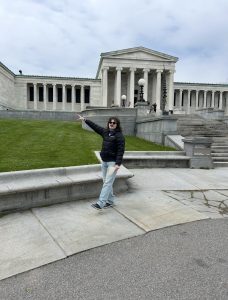 Male college student standing with his arm pointing toward a historic building