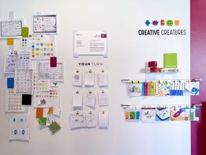 Multiple sketches, text and artwork displayed on a wall