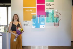 Woman standing holding a bouquet of flowers next to artwork on the wall