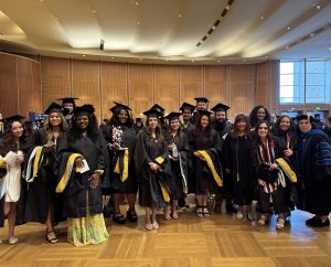 A group of men and women wearing graduation caps and gowns standing in a room together