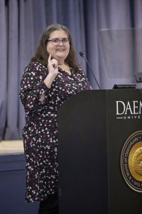 Woman wearing a dress standing behind a podium talking