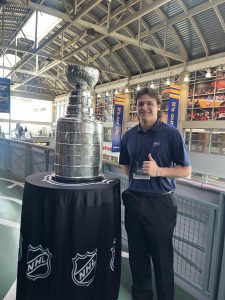 Male college student standing next to the Stanley Cup.