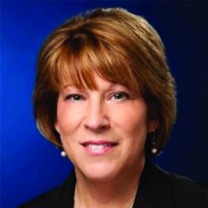 Headshot of woman with short light brown hair in front of a dark blue background
