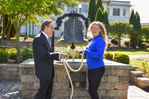 President Olson standing with a female college student in front of Founders Bell on Daemen's campus.