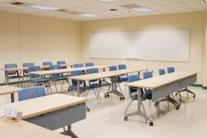 Classroom with tables, chairs and white boards mounted on the wall
