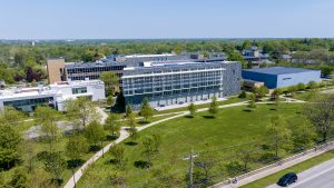 Aerial shot of the front of Daemen University's campus, showing buildings, green space, trees, sidewalks and the street