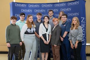 10 Daemen students standing together in front of a blue Daemen step-and-repeat backdrop