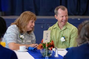 Man and woman sitting together at a dinner table interacting with other people