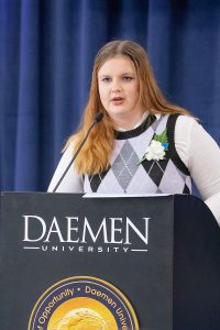 Female Daemen student standing behind a podium speaking