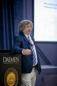 Man leaning against a podium talking to an audience