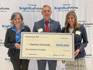 Lisa Rafalson, Greg Ford, and Robin King hold an oversized check in front of a step and repeat background